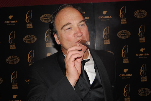 Jim Belushi in a tuxedo, enjoying a cigar at a formal event