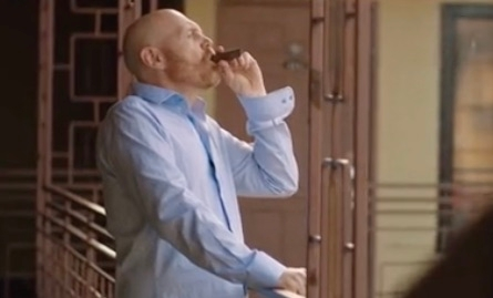 Bill Burr enjoying a cigar on a balcony