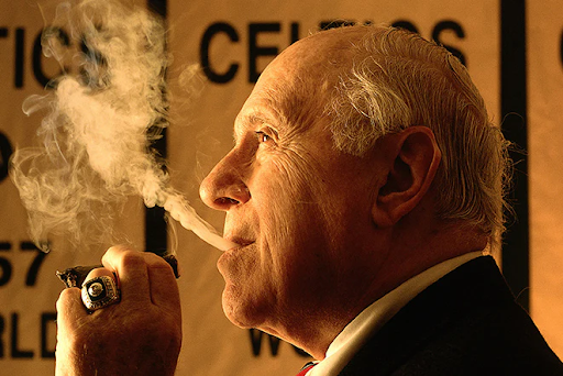 Red Auerbach enjoying a cigar, embodying confidence and charisma